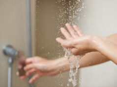 Para que lado você deve ficar no chuveiro? Especialistas resolvem o debate As mãos de uma pessoa pegando água de um chuveiro.