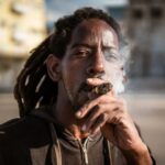 Um morador de Havana fuma um charuto enquanto pesca no Malecón. (Euan Wallace/Al Jazeera)
