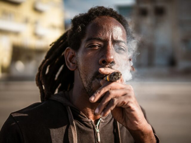 Poderá o bloqueio petrolífero dos EUA apagar o charuto cubano? Um morador de Havana fuma um charuto enquanto pesca no Malecón. (Euan Wallace/Al Jazeera)