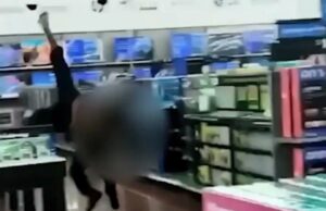 Policial da Geórgia foi afastado após agredir homem no Walmart: ‘Pensei que ele estivesse morto’ Um policial de uniforme escuro fica de costas para a câmera dentro de uma loja, com clientes e mercadorias visíveis ao seu redor.