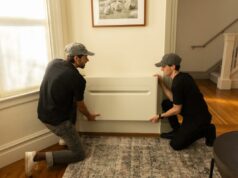 Por que um ex-engenheiro de AirPods está agora construindo bombas de calor Two men install a heat pump on a wall.