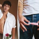 Kosas Lip Pulse Glossy Lip Plumper em um tubo rosa claro com fundo texturizado em azul claro, contra uma mancha de brilho labial rosa claro.