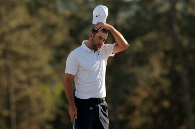 Scottie Scheffler tira o boné branco, segurando-o logo acima da cabeça, e parece frustrado no buraco 18 do Masters.