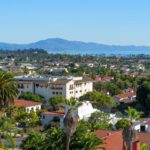 Panorama de alto ângulo de Santa Bárbara mostrando a cidade, as palmeiras e o Oceano Pacífico com montanhas ao fundo.