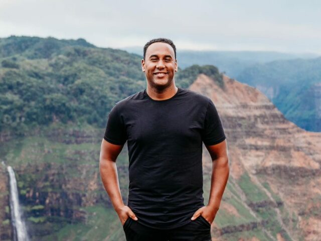 Quatro Jeep Wranglers alinhados com colinas verdes e água ao fundo.