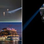 Um navio de cruzeiro à noite com um feixe de holofote brilhando na água escura e uma bóia salva-vidas pendurada na lateral do navio.