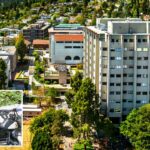 Um policial uniformizado parado ao lado de uma motocicleta e um carro da polícia no campus da UC Berkeley.