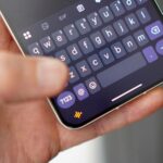 Uma mulher sentada usando o assistente de voz em seu telefone, com um robô de IA ao lado dela.