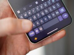 Um futuro que prioriza a voz parece exaustivo, então não pare de digitar Uma mulher sentada usando o assistente de voz em seu telefone, com um robô de IA ao lado dela.