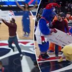 Um fã posando para uma foto com os mascotes do Washington Wizards e um cheque falso de US$ 10 mil por uma pegadinha do Dia da Mentira.