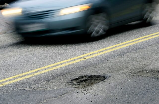 CAPE ELIZABETH, ME - FEBRUARY 22: A car drives past a pothole on Forest Ave. in Portland Tuesday, February 22, 2022. (Shawn Patrick Ouellette/Portland Press Herald via Getty Images)