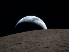 A NASA diz que colocará humanos na superfície da Lua em 2028. Quão realista é isso? Um foguete alto pousa em uma plataforma de lançamento em um dia nublado, cercado por areia, um pouco de grama verde e água.