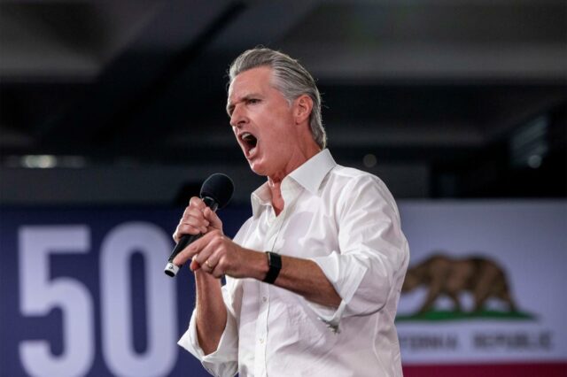 O governador da Califórnia, Gavin Newsom, falando ao microfone com a boca aberta.