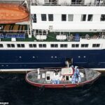 Vista aérea mostra profissionais de saúde a ajudar pacientes num barco do navio de cruzeiro MV Hondius, enquanto estacionava ao largo do porto da Praia