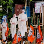 O primeiro-ministro Narendra Modi (centro) acena para os apoiadores que comemoram a vitória do BJP nas eleições para a assembleia estadual recentemente realizadas.