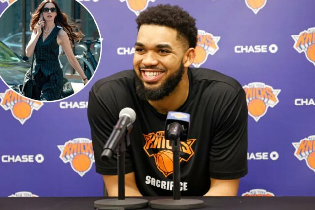 Karl-Anthony Towns sorrindo em uma coletiva de imprensa com dois microfones à sua frente.
