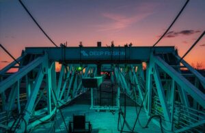 A startup nuclear Deep Fission diz que vai abrir o capital novamente e eu tenho dúvidas A drilling rig stands in front of a sunset.