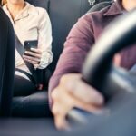 imagem de uma pessoa ao telefone no banco de trás com um motorista ao volante