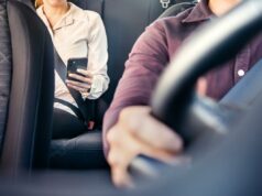 Adolescente de Long Island estuprada em Nova York depois que o motorista do Uber não conseguiu verificar a identidade, afirma a família imagem de uma pessoa ao telefone no banco de trás com um motorista ao volante