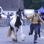 Centenas de viajantes chegaram a uma vila geralmente pacata de Hampshire para a Feira Anual de Cavalos de Wickham (um menino é fotografado correndo por uma rua fechada com um pônei)