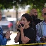 Foto de Gregory Bull / AP - FOTO: Pessoas atrás de fita policial no local de um tiroteio fora do Centro Islâmico de San Diego, 18 de maio de 2026.