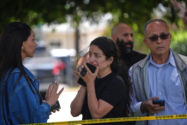 Foto de Gregory Bull / AP - FOTO: Pessoas atrás de fita policial no local de um tiroteio fora do Centro Islâmico de San Diego, 18 de maio de 2026.