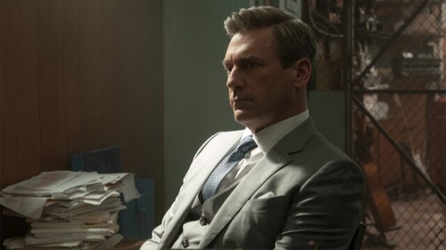A man in a grey suit sitting down and looking sad