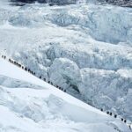 Alpinistas caminham em uma longa fila enquanto se dirigem ao cume do Monte Everest, no distrito de Solukhumbu, também conhecido como região do Everest, Nepal, 18 de maio de 2026