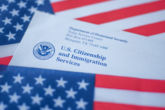 Washington, DC, USA - September, 16, 2019: Letter from USCIS covered in flag of USA on American colors background - stock photo