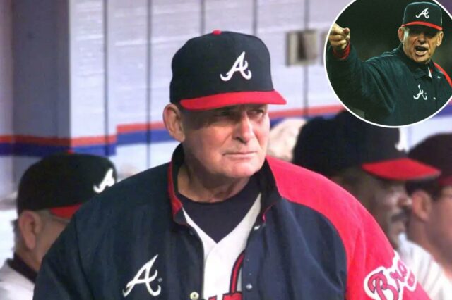 Bobby Cox com uniforme do Braves, segurando uma xícara e papéis no banco de reservas.