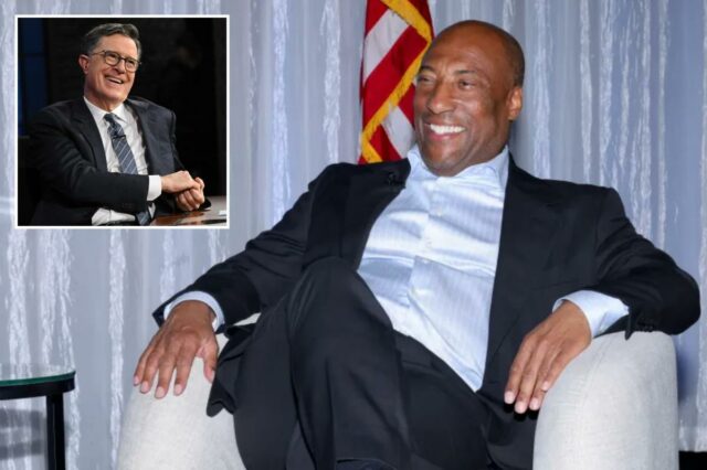 Byron Allen sorrindo sentado em uma poltrona.