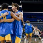 Quatro jogadores de vôlei masculinos com camisetas azuis e douradas se amontoam, abraçados.