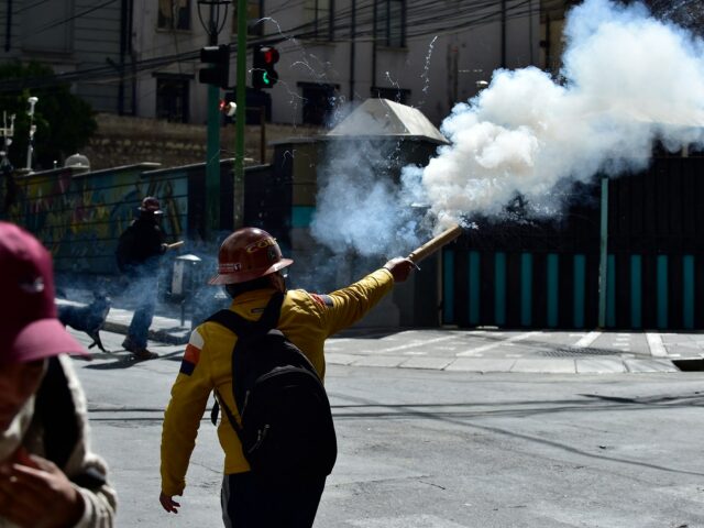 As chamas sobem de uma caixa de papelão enquanto mineiros entram em confronto com a tropa de choque durante um protesto exigindo a renúncia do presidente boliviano Rodrigo Paz, em La Paz, em 18 de maio de 2026.