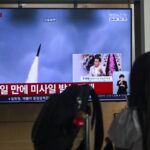 A woman watches a television screen showing a news broadcast with file footage of a North Korean missile test, at a train station in Seoul on May 26, 2026.