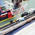 Pelo menos cinco pessoas com equipamento de proteção completo, macacão branco, botas e máscaras faciais, foram vistas desembarcando do navio em uma pequena embarcação