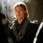 A man with long blonde hair looks serious and concerned