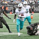 O running back dos Dolphins, De'Von Achane (28), corre a bola para um touchdown durante o primeiro quarto no jogo Jets e Miami Dolphins em East Rutherford, NJ.