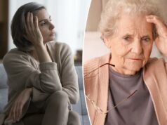 Dois sinais sutis de Alzheimer podem aparecer já aos 45 anos Uma senhora idosa de cabelos grisalhos, vestida com um cardigã cor de pêssego e uma camisa cinza, está sentada em uma cama com a mão na cabeça e os óculos na outra, parecendo angustiada.