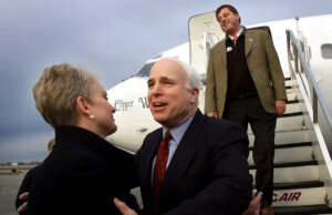 Doug McCain, filho mais velho do senador John McCain, morre aos 66 anos Sonhar. John McCain estende a mão para sua esposa Cindy, acompanhado pelo filho, Doug McCain, quando o então candidato presidencial republicano chega a Syracuse, Nova York, em 4 de março de 2000.