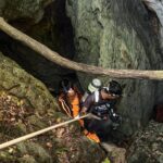 Esta imagem divulgada por Metta Tham Rescue Kalasin em 26 de maio de 2026 mostra equipes de resgate falando do lado de fora de uma caverna na província de Xaisomboun.