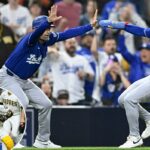 O apanhador do San Diego Padres, Austin Nola, lança para uma base enquanto o arremessador Joe Musgrove observa.