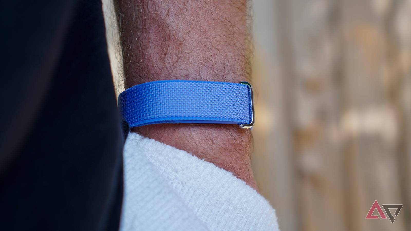 Mulher usando uma faixa de fitness Fitbit Air azul com faixas coloridas flutuando no fundo.