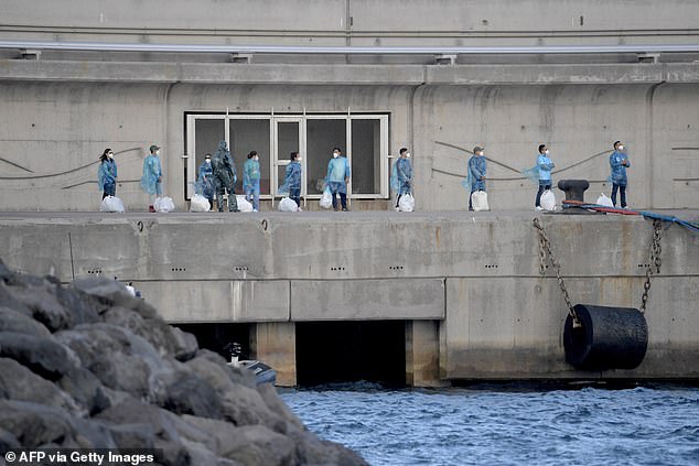 Foi confirmado que outro hantavírus evacuado de um cruzeiro tem Pessoas com trajes de proteção esperam na fila após desembarcar do navio de cruzeiro MV Hondius, infectado pelo hantavírus, atracado no porto de Granadilla de Abona, na ilha de Tenerife, nas Ilhas Canárias, na Espanha, em 11 de maio.