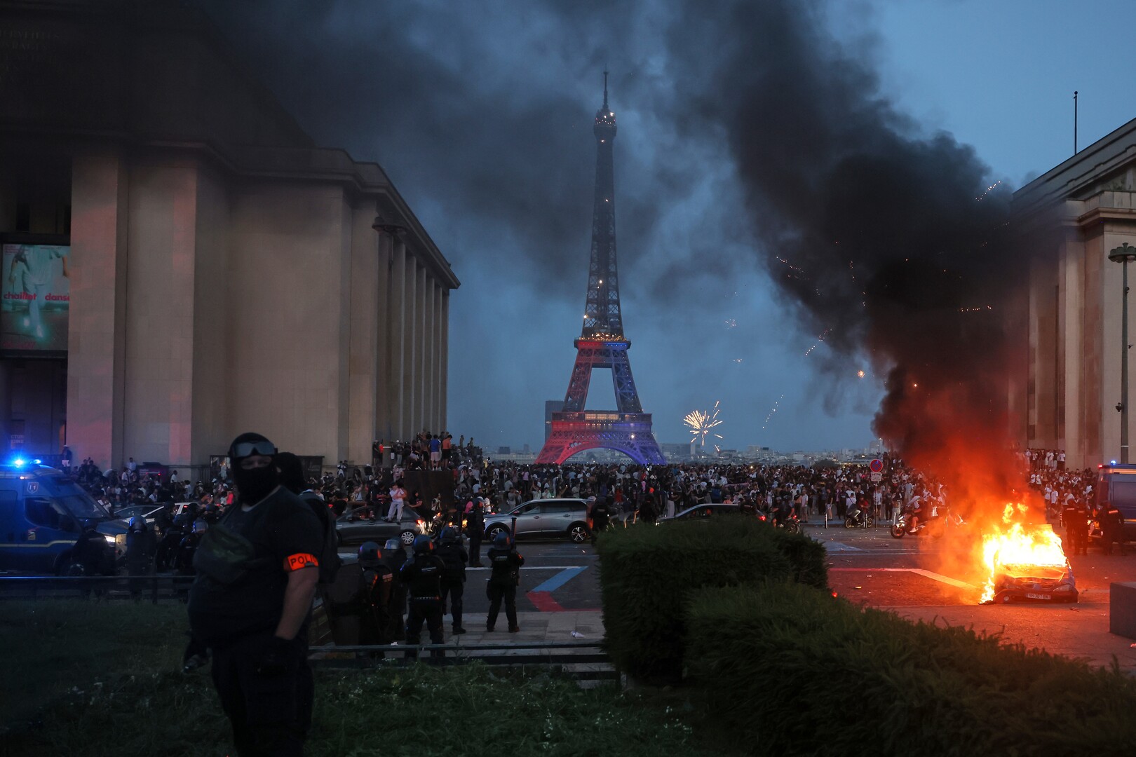 Os adeptos do PSG passam com as suas scooters pelos agentes da polícia anti-motim (traseira direita) enquanto celebram a vitória da sua equipa na final da UEFA Champions League entre o Paris Saint-Germain (PSG) e o Arsenal FC, disputada em Budapeste, na Place du Trocadero, em Paris, a 30 de maio de 2026.