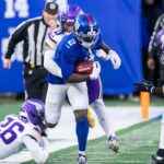 O jogador do New York Giants, Deonte Banks, corre a bola enquanto o jogador do Minnesota Vikings, Ivan Pace Jr., o aborda.