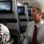 Um comissário de bordo oferece aos passageiros lanches em uma cesta em um avião.