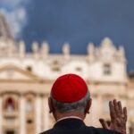 A cardinal gestures as he arrives for a congregation meeting at the Vatican with a view of the St. Peter's Basilica in the background on May 6, 2025.