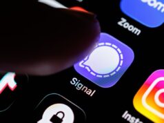 Hackers estão tentando roubar backups de usuários do Signal em nova onda de ataques de phishing The Signal app logo can be seen on the display of a smartphone while a finger taps on the application icon.