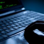 Hacker using laptop. Lots of digits on the computer screen.