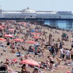 Vista da praia enquanto as pessoas aproveitam o clima quente em Brighton, East Sussex
